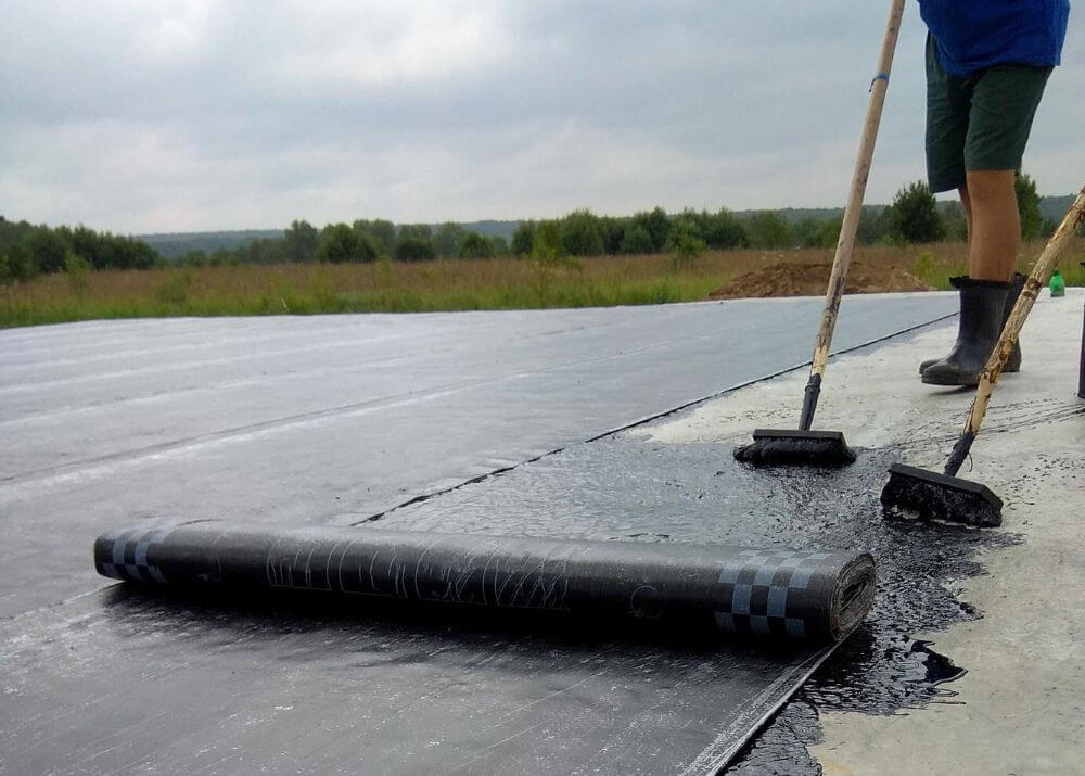 Torch-on felt being laid onto a flat roof deck in Fulham